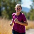 Smiling woman Maria, 39, jogging along a scenic trail